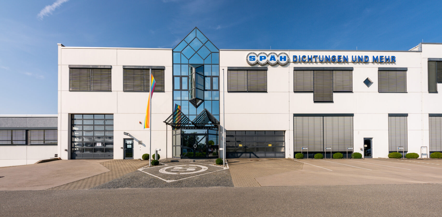 Die Außenansicht eines modernen weißen Firmengebäudes unter blauem Himmel zeigt den Schriftzug 