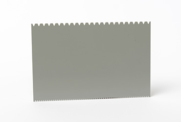 Eine graue, rechteckige Platte besitzt eine charakteristische Sägezahnkante am oberen Rand.