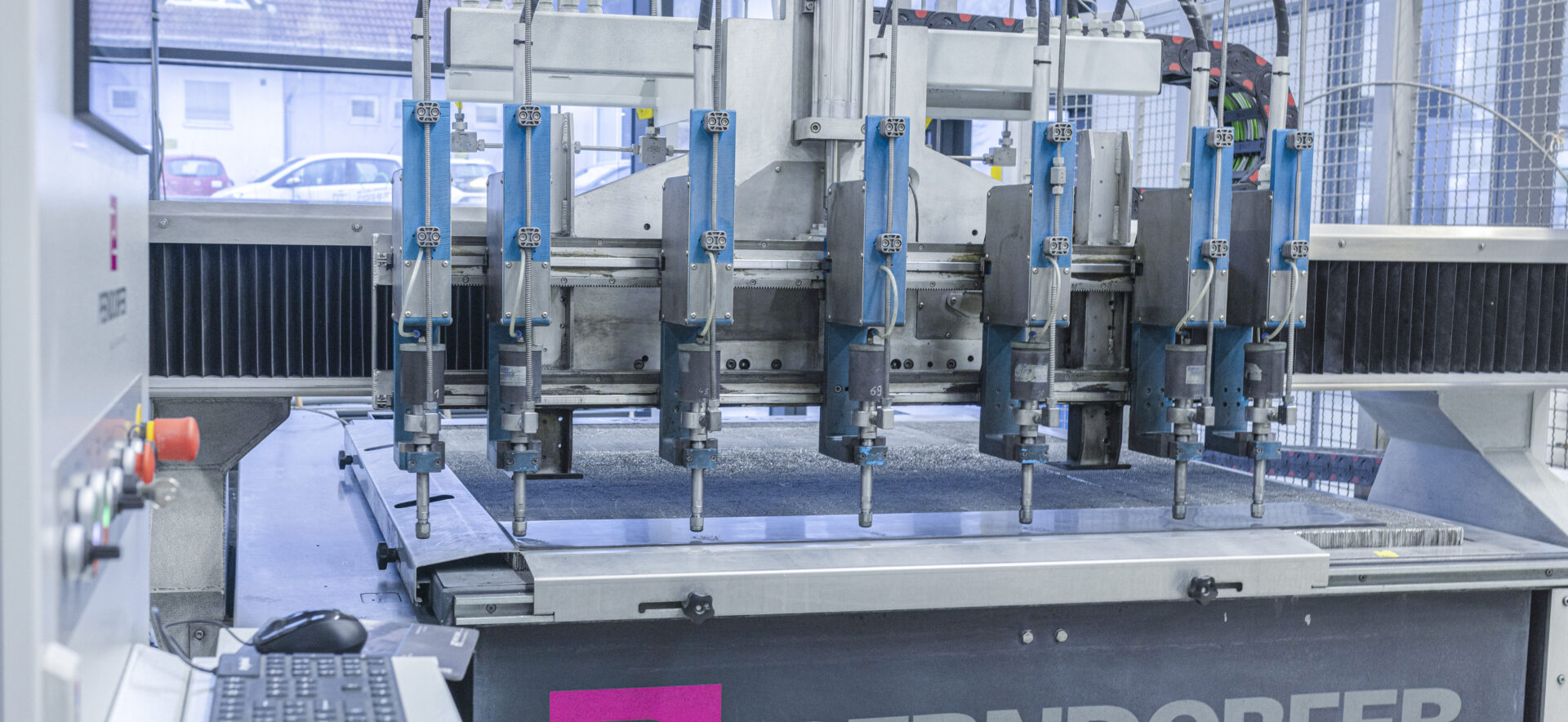 Ein Wasserstrahlschneider mit mehreren Köpfen ist in der Fertigungshalle von Späh bei der Bearbeitung eines Plattenmaterials zu sehen.