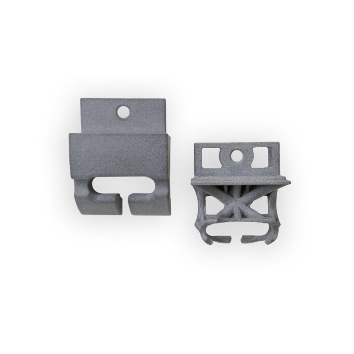 Zwei graue, dreidimensional gedruckte Halterungen mit unterschiedlicher Form liegen als gefertigte Teile auf einem weißen Hintergrund.