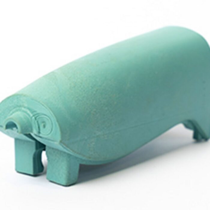 Abgebildet ist ein komplex geformtes, matt-türkisfarbenes Kunststoffbauteil mit verschiedenen Aussparungen und Standfüßen.