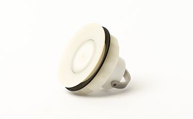 Ein präzise gefertigtes Bauteil aus weißem Kunststoff mit einer umlaufenden schwarzen Dichtung und einem metallischen Befestigungsbügel liegt als fertiges Werkstück auf einem weißen Hintergrund.