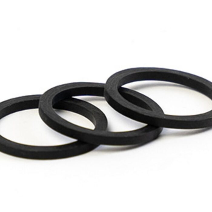 Drei flache, schwarze Ringe aus Gummi liegen leicht überlappend in einer Reihe.