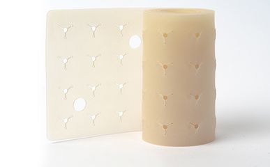 Die Abbildung zeigt eine beigefarbene, zylindrische Rolle aus einem Material, das an der Oberfläche mit einem wiederholten, dreifach angeordneten Vertiefungsmuster bearbeitet wurde.