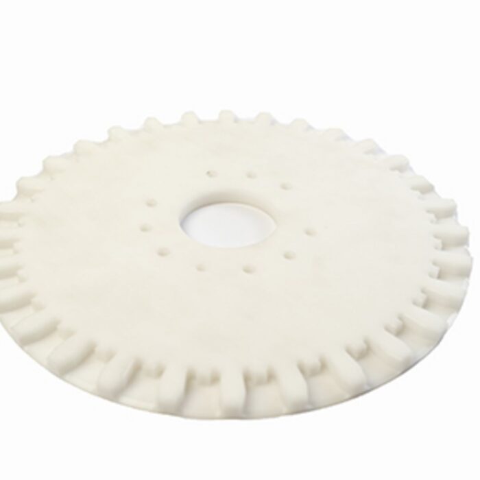 Ein weißes, kreisförmiges Bauteil aus Kunststoff weist eine markante Zahnung am äußeren Rand und eine zentrale Bohrung auf.