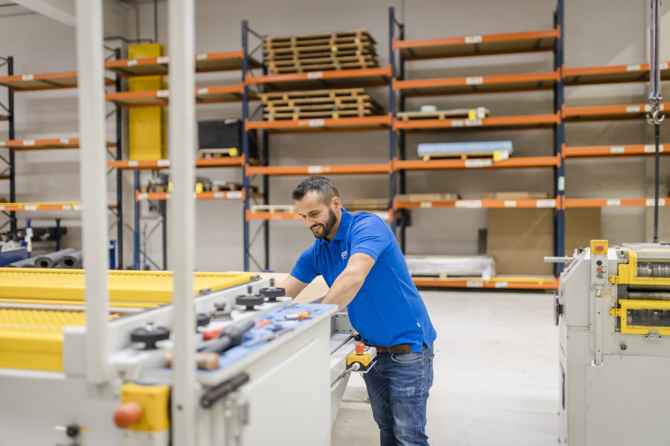 Ein lächelnder Späh-Mitarbeiter der eine Maschine bedient aus der Vorfertigung.