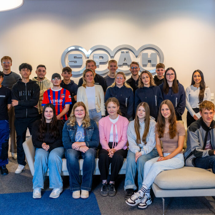 Gruppenfoto mit allen Auszubildenden bei dem alle Neuen auf dem Sofa sitzen und die älteren Auszubildenden hinter dem Sofa stehen.
