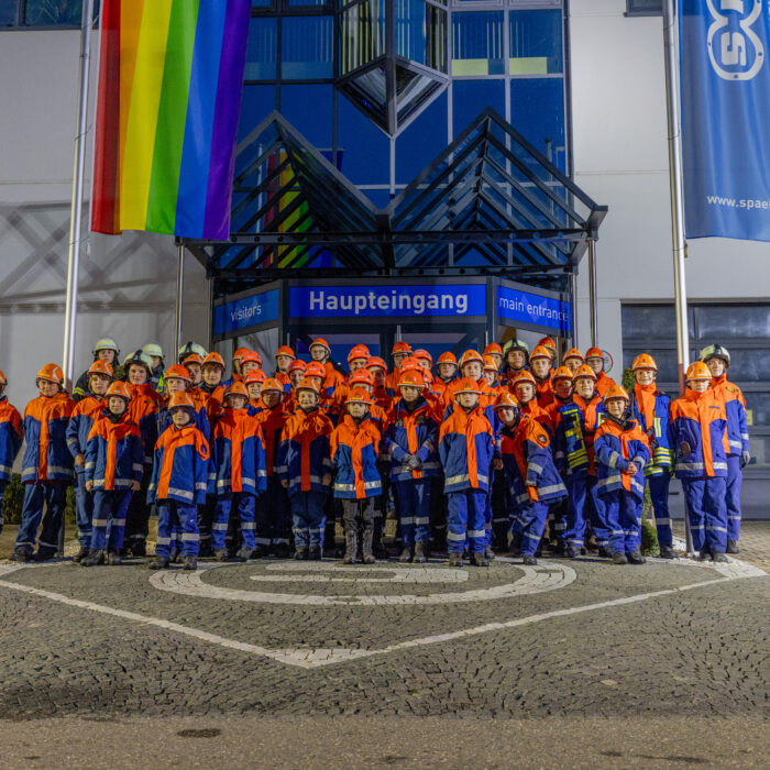 Gruppenfoto von vielen Kindern aus der Jugendfeuerwehr vor dem Haupteingang von Späh. Alle Kinder sind einheitlich in ihrer Jugendfeuerwehrkleidung.