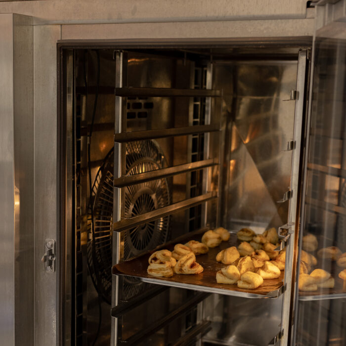 Ein volles Backblech mit Weihnachtsgebäck ist im Ofen. Die Tür vom Ofen ist offen.
