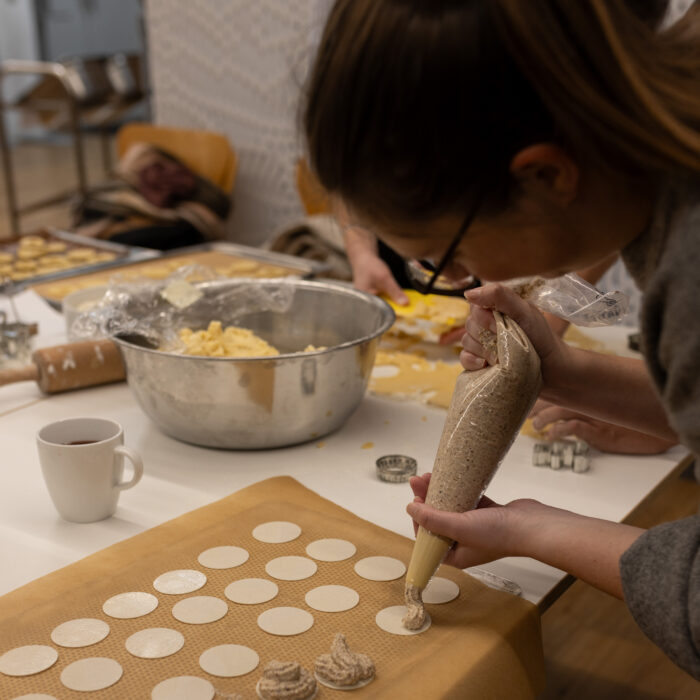 Eine Späh-Mitarbeiterin steht vor einem Backblech und gibt Spritzgebäck auf das Blech.