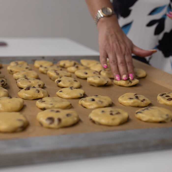 Auf dem Tisch ist ein volles Backblech mit Weihnachtsgebäck. Ein Späh-Mitarbeiter hat die Hand auf eines der Leckereien.