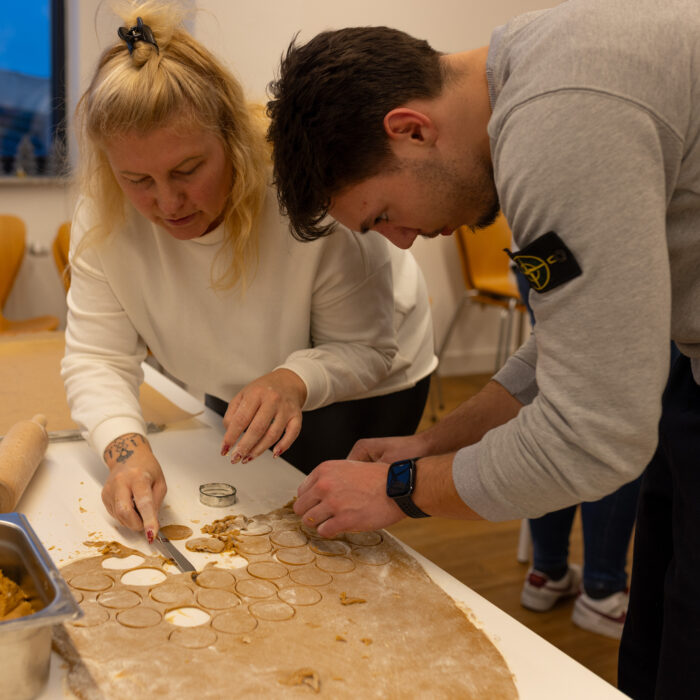 Zwei Späh-Mitarbeiter in der Kantine beim Ausstechen von Plätzchen. Die fertigen ausgestochenen Plätzchen sind auf einem Backblech.